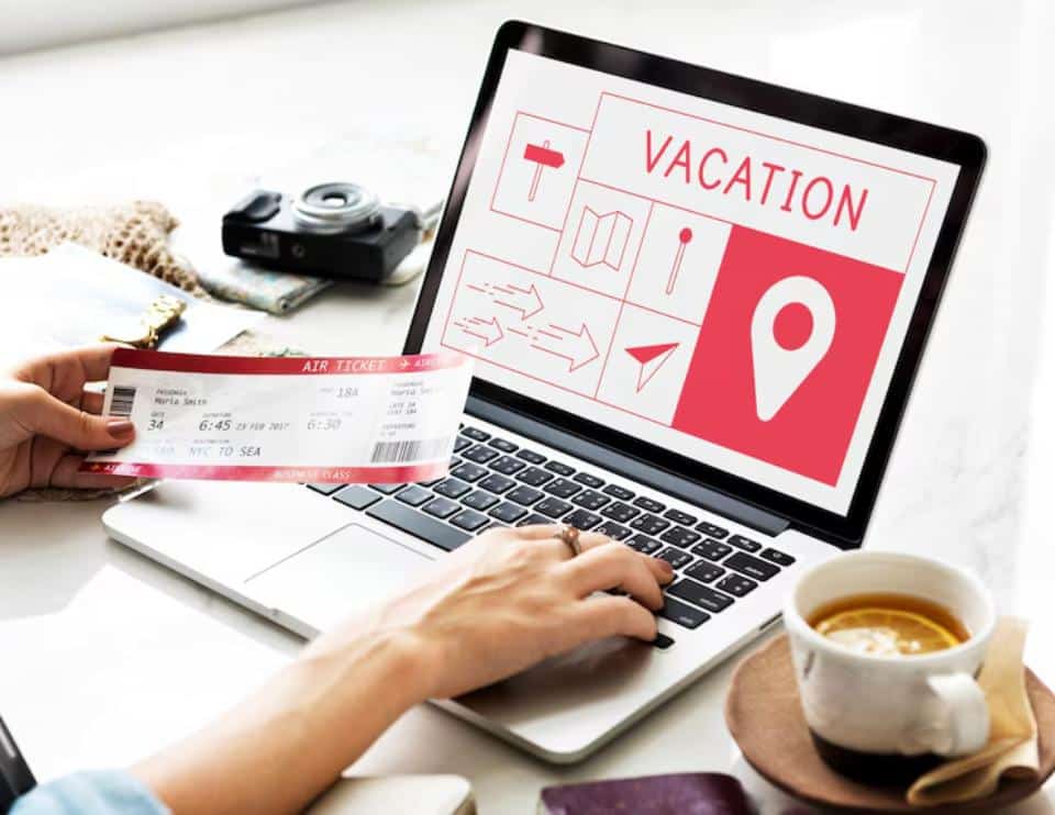 A person holds an airline ticket while using a laptop displaying a