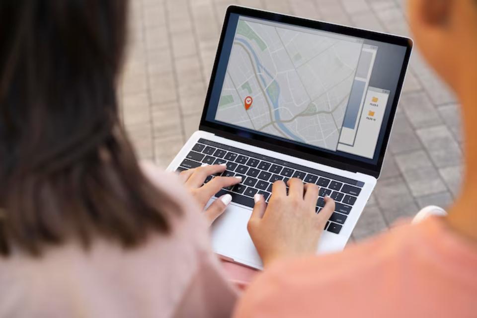  A person navigating a digital map on a laptop outdoors, with hands on the keyboard and a map displayed on the screen.