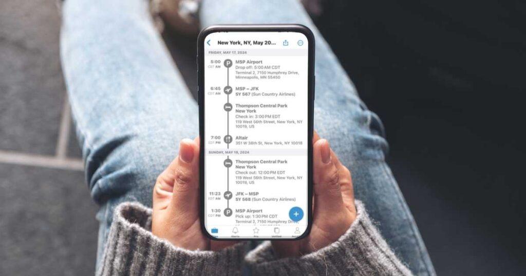  A person holds a smartphone displaying a travel itinerary for New York, including flights and hotel check-in details.
