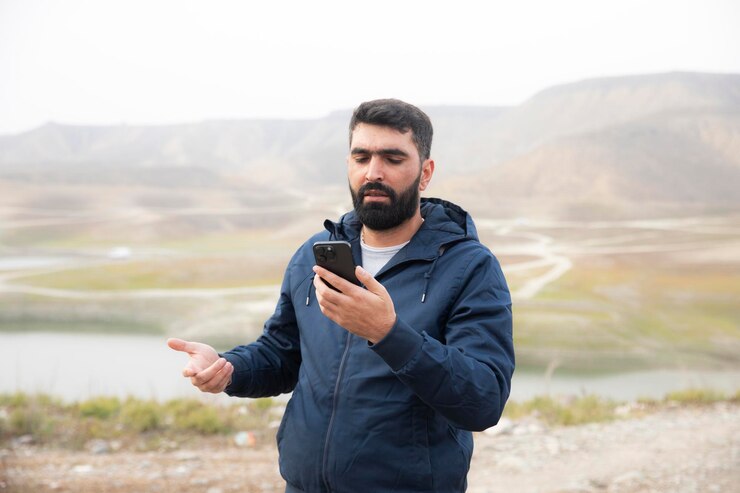  A person holds a smartphone in a remote area looking for networks.